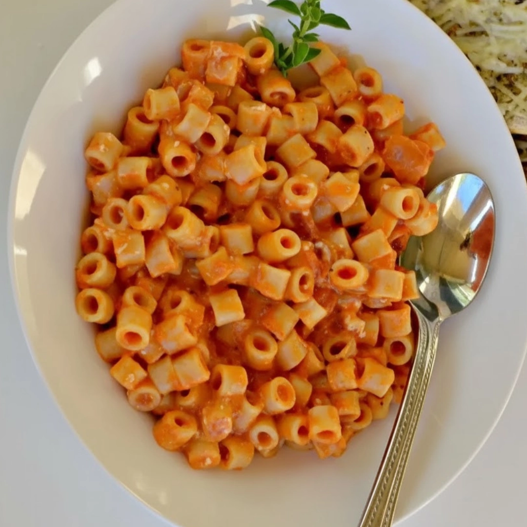 Ditalini pasta served in a bowl with basil and cheese