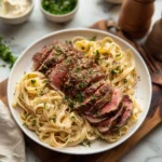 Steak pasta in a white bowl with creamy sauce