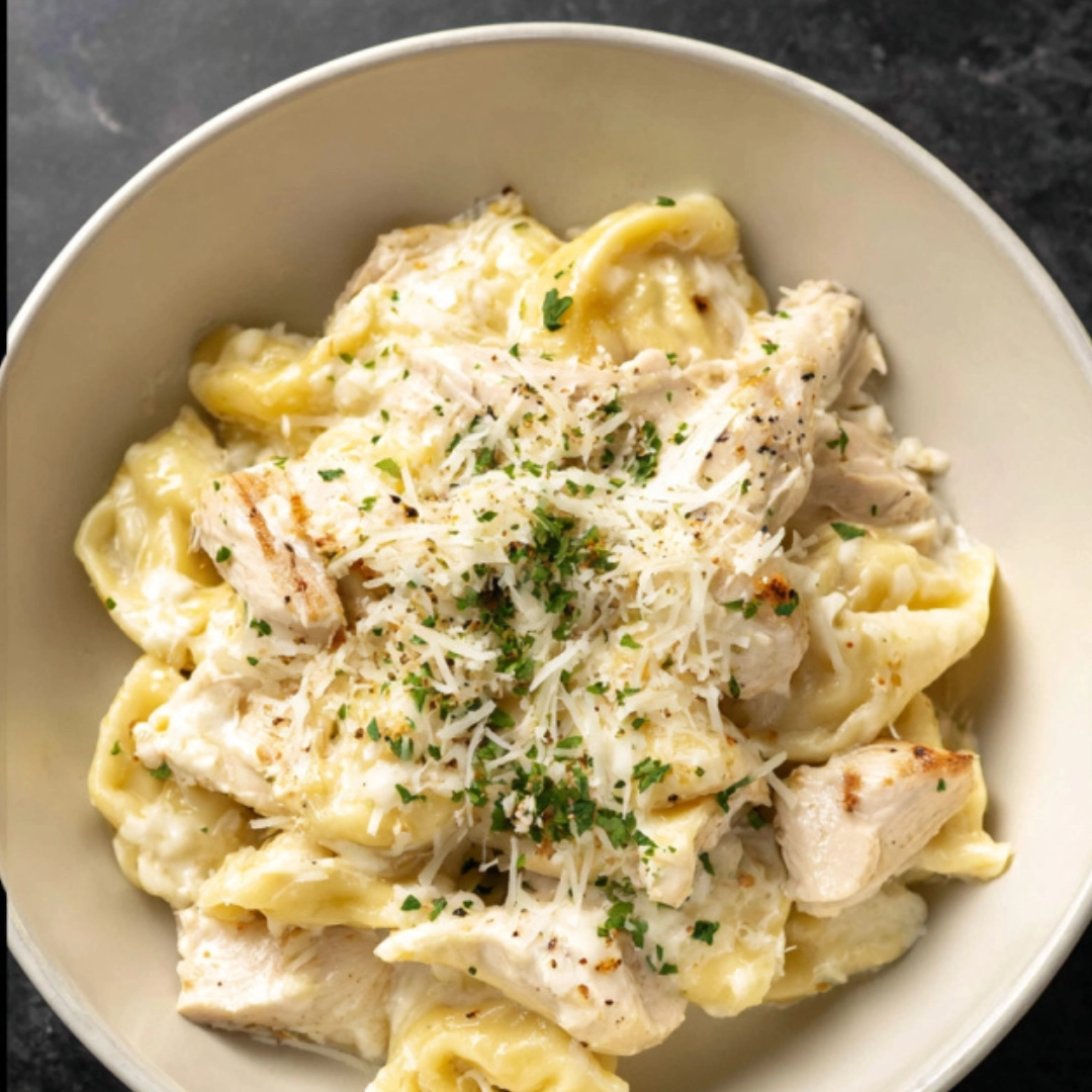 Creamy chicken tortellini Alfredo sauce with freshly grated parmesan cheese in a skillet