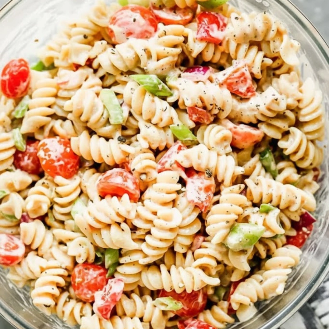 Bowl of creamy Italian pasta salad with tri-color rotini, mozzarella, black olives, and fresh herbs