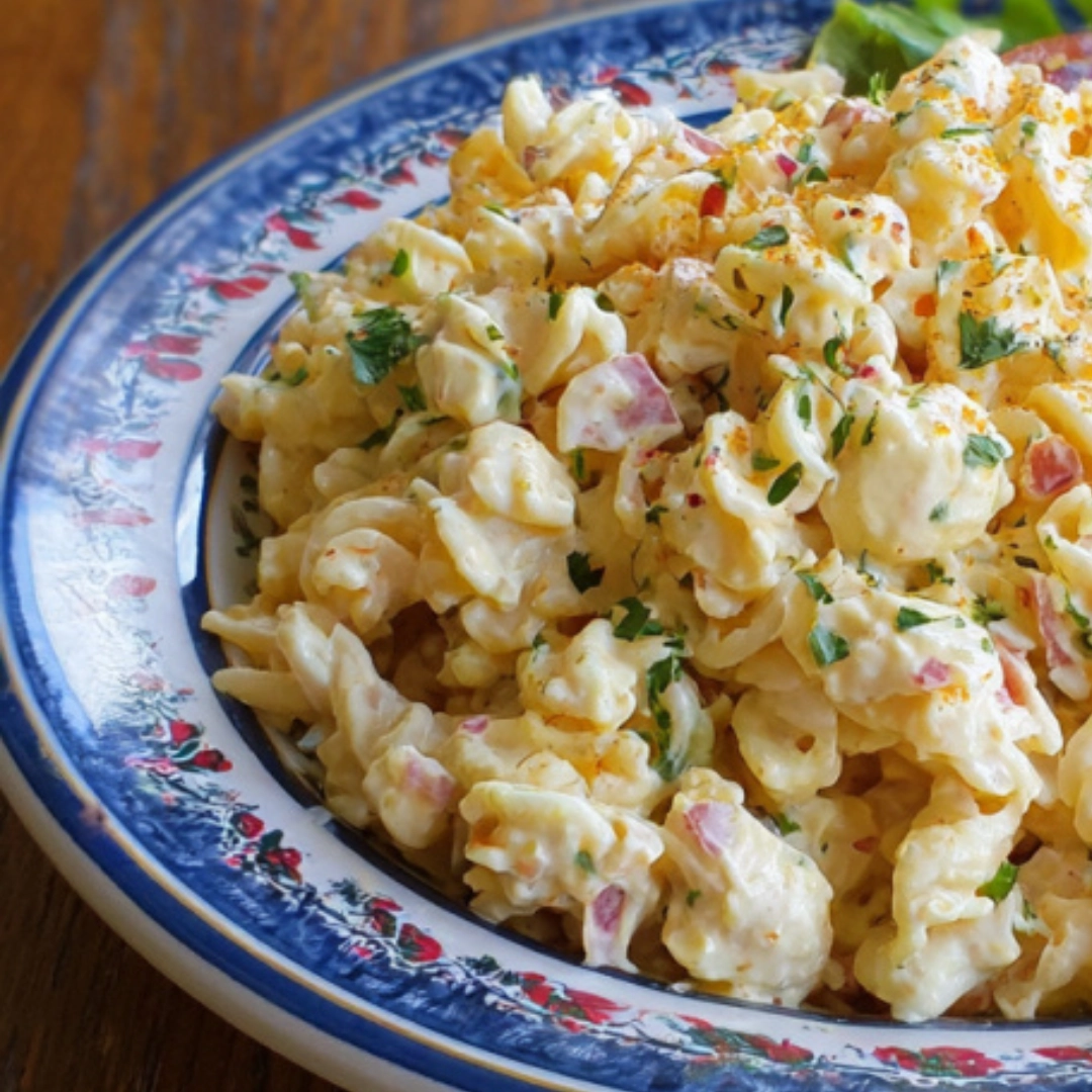 classic-deviled-egg-pasta-salad-close-up.webp Close-up of creamy deviled egg pasta salad loaded with red onions and fresh herbs