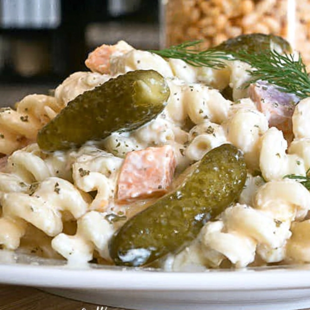 dill-pickle-pasta-salad-plated-with-whole-pickles Ingredients for dill pickle pasta salad recipe including pickles, cheddar, rotini, and fresh dill