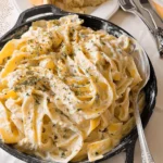 Creamy philadelphia cream cheese pasta served in a black skillet with fresh herbs on top