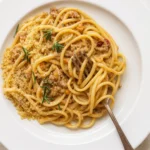 white spaghetti bolognese plated with parmesan and herbs
