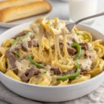 A baked casserole dish of creamy Cheesesteak Tortellini topped with golden melted cheese.