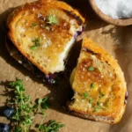 Stacked halves of a golden-brown Gourmet Blueberry Grilled Cheese showing the melted white cheddar and compote filling.