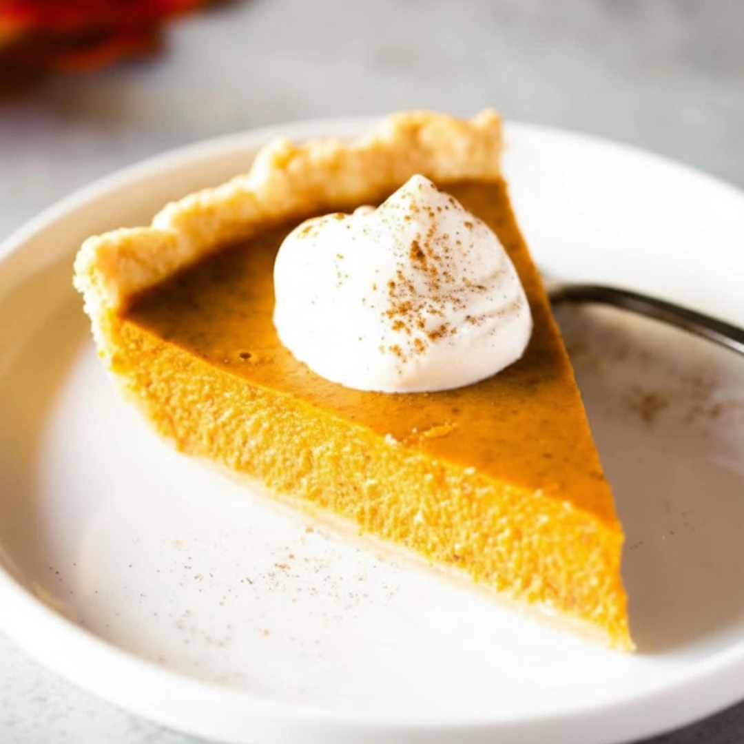 Slice of perfect homemade pumpkin pie on a plate with a dollop of whipped cream.