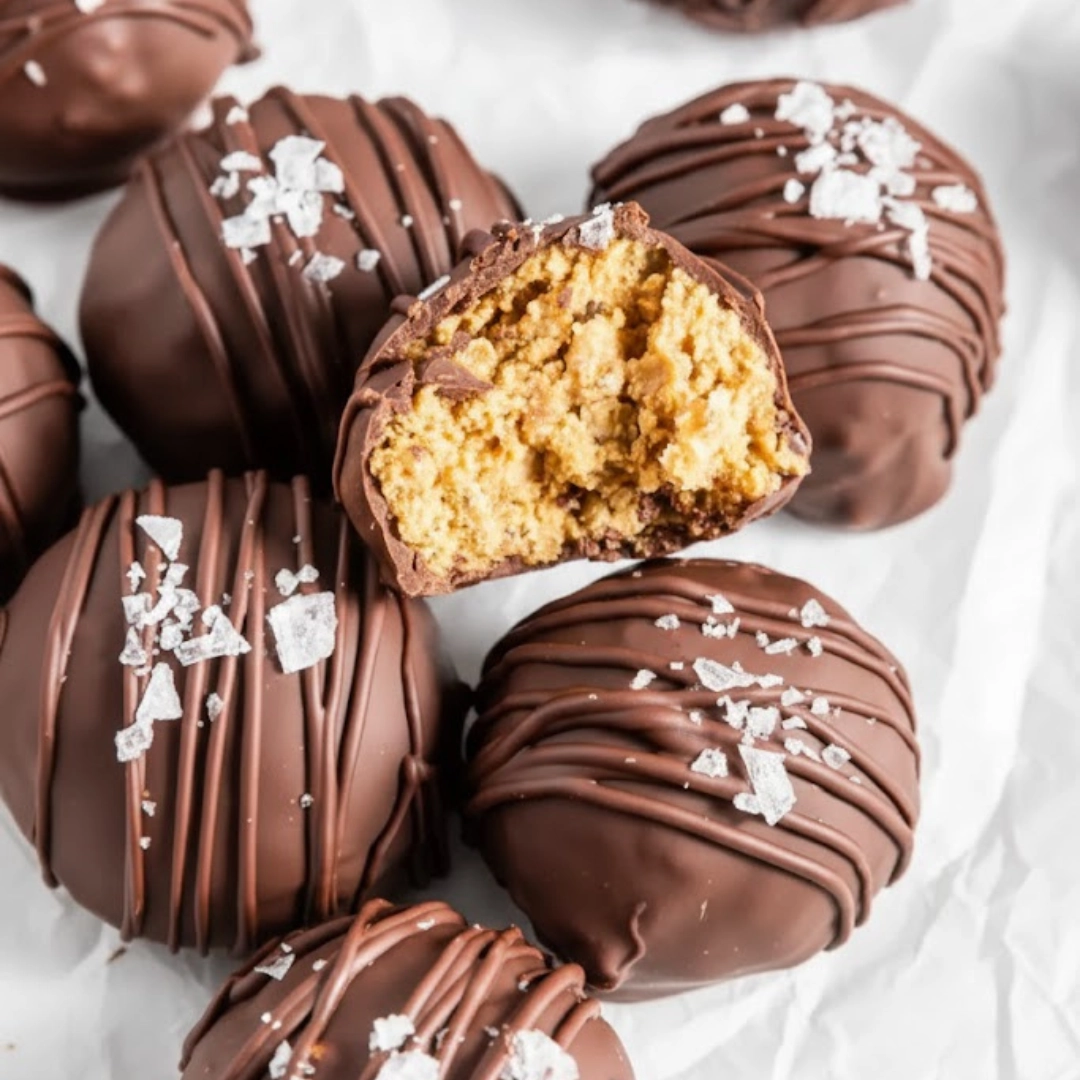 Stack of homemade crunchy chocolate balls on a white platter, showing the interior texture and glossy finish.