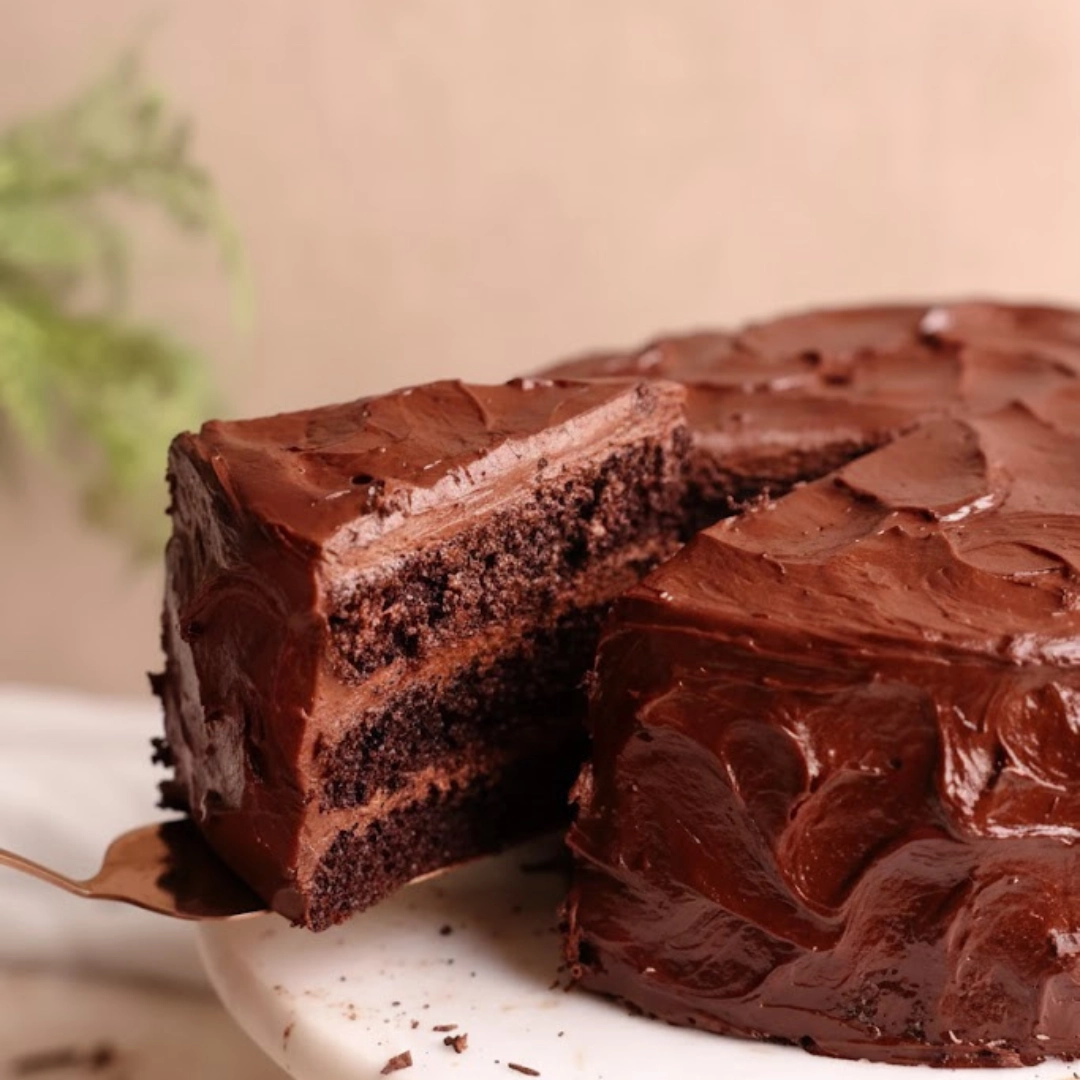 Slice of rich, fudgy Matilda Chocolate Cake Recipe with glossy frosting on a plate.