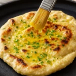 Soft gluten-free naan bread stacked on a wooden board