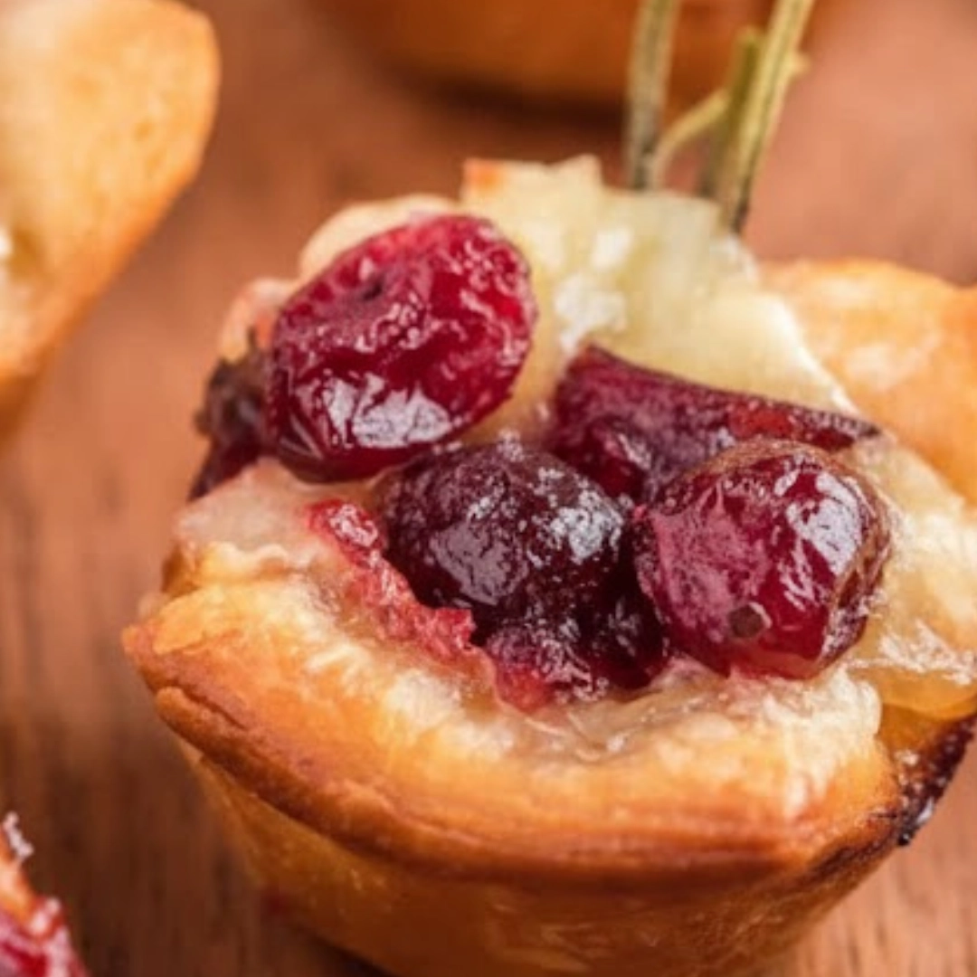 Close-up of golden brown Baked Cranberry Brie Bites topped with fresh thyme and honey drizzle