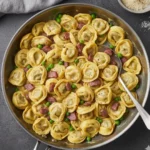 A close-up shot of creamy Tortellini Carbonara garnished with fresh parsley and black pepper in a bowl.
